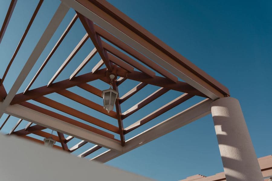 Low-angle view of a geometric aluminum pergola structure against a clear sky