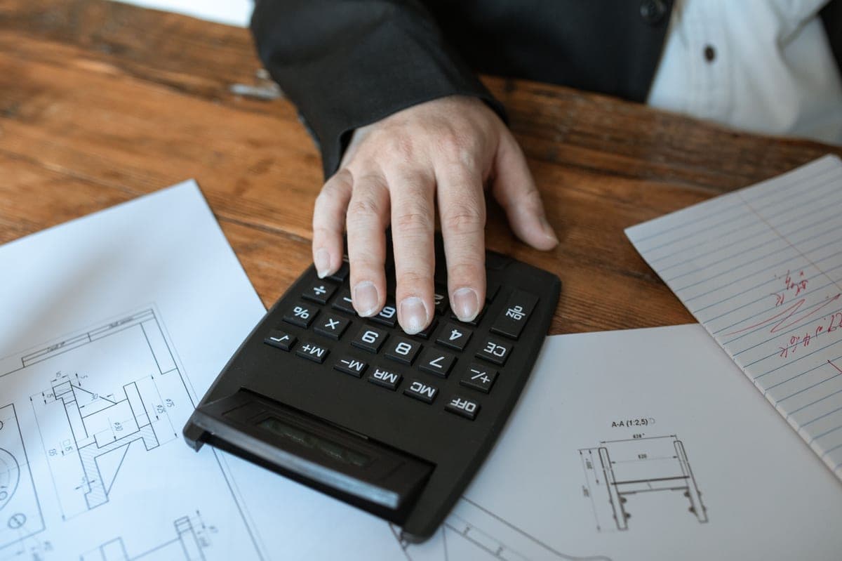 Calculator and notes on a desk beside project plans
