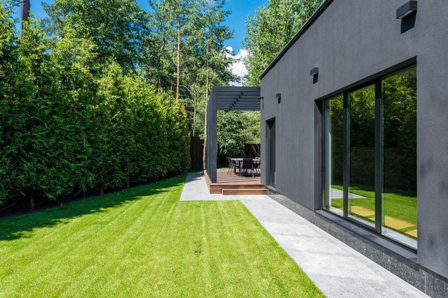 Modern house exterior with a raised timber deck and outdoor seating in a green yard