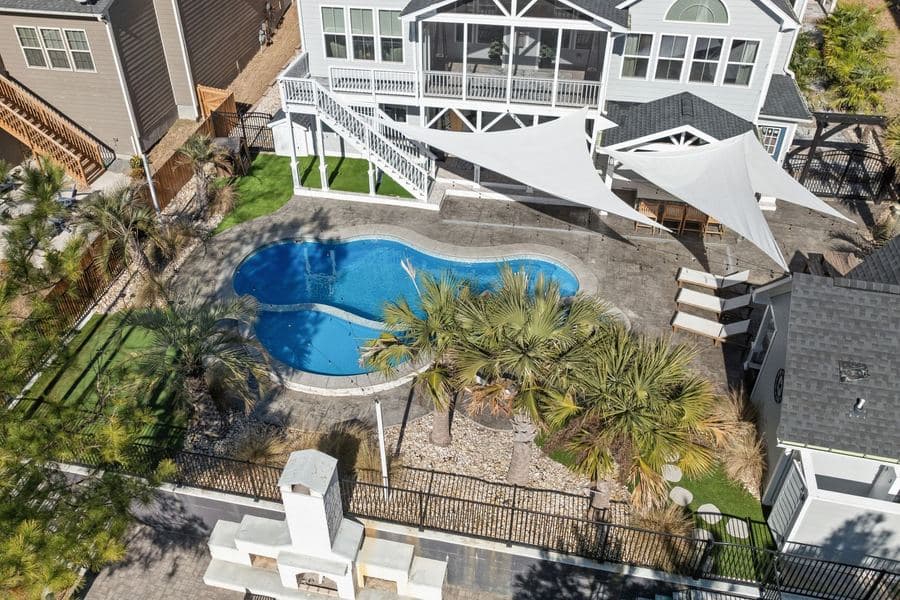 Shade sail tensioned above a timber deck with outdoor seating and a railing below