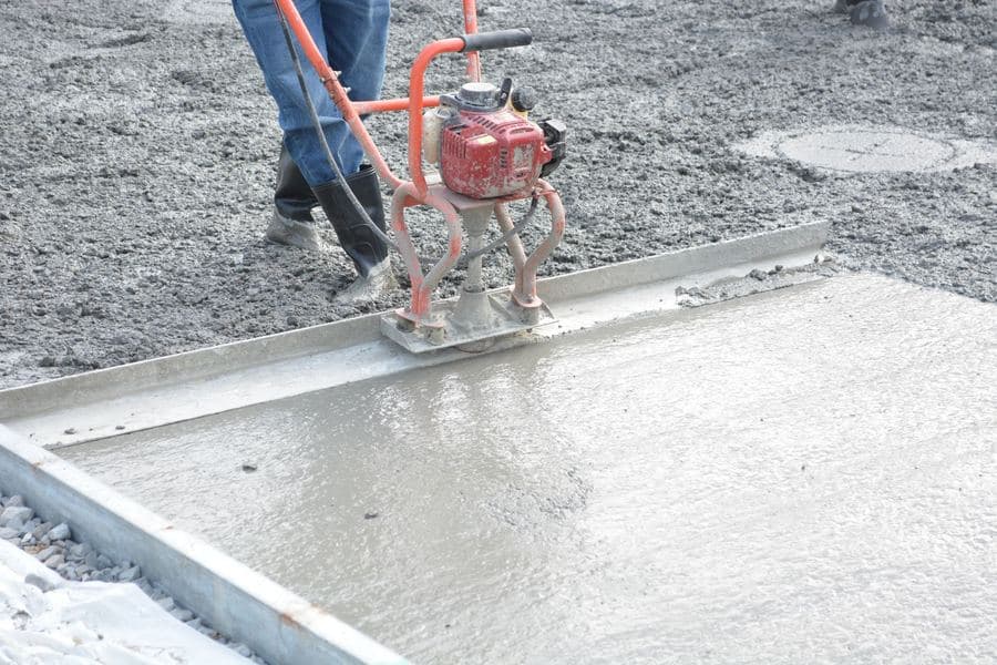 Freshly poured concrete slab being screeded and power-floated inside timber formwork