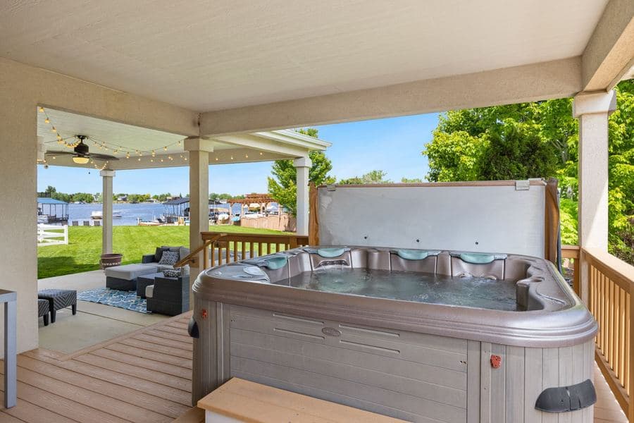 Outdoor hot tub on a timber terrace overlooking open water in daylight