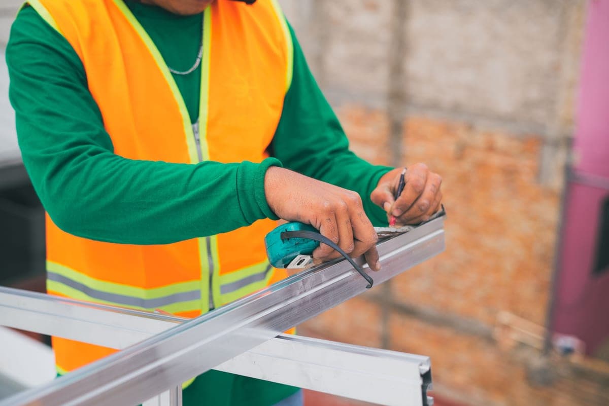 Person fitting hardware to the base of an outdoor structure with hand tools