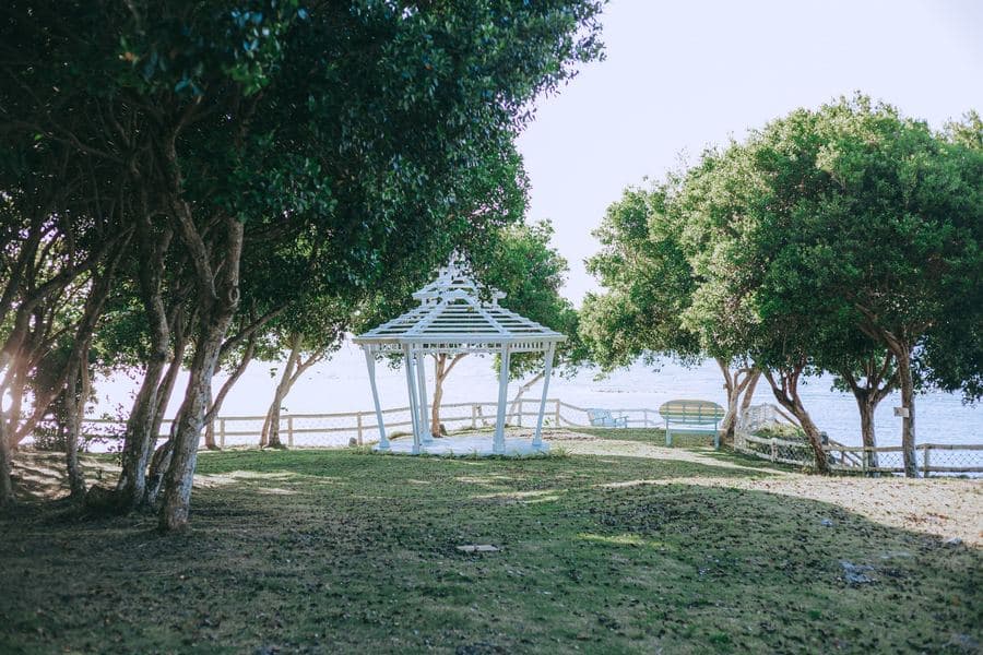 Large gazebo with a pitched roof standing on a lawn beside a garden seating area