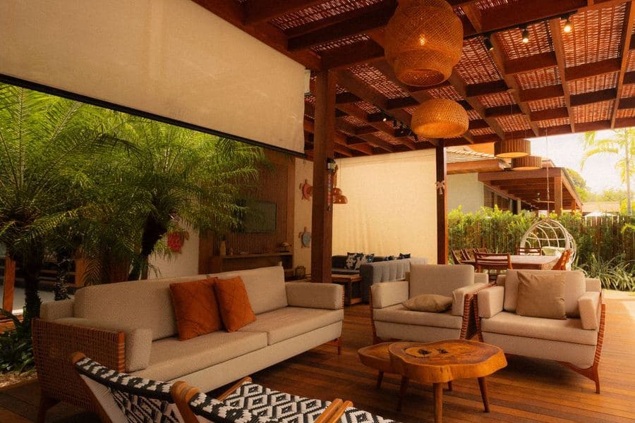Slatted-roof outdoor living room with sofas and timber beams open to a planted garden