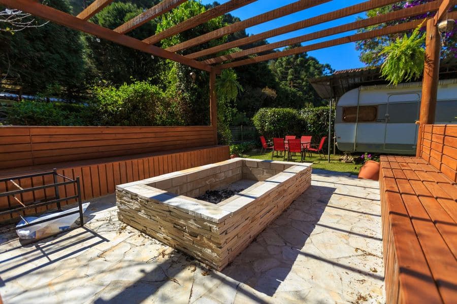 Aluminum pergola with a closed solid roof over a furnished patio beside a house wall