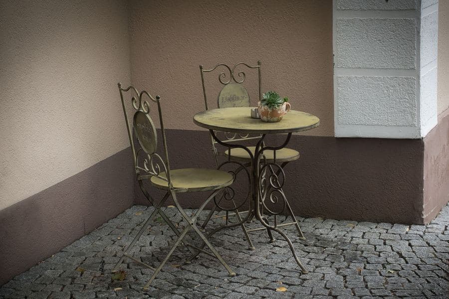 Compact paved courtyard patio with a small seating set against a rendered garden wall