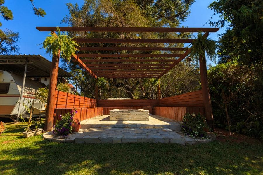 Timber garden structure surrounded by mature planting on a bright day