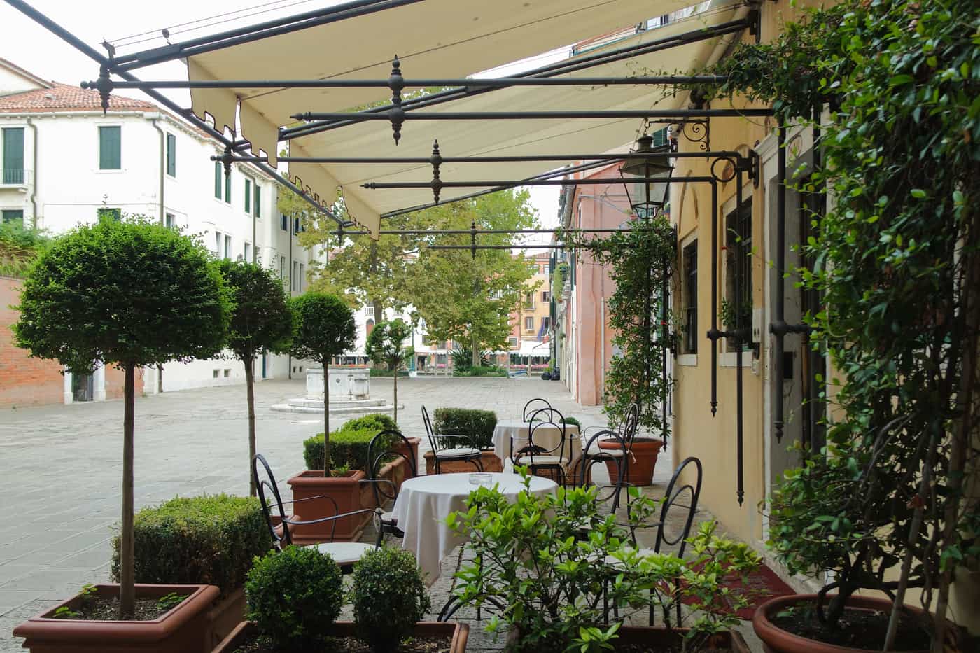 Retractable patio awning extended over a paved terrace beside a house in daylight