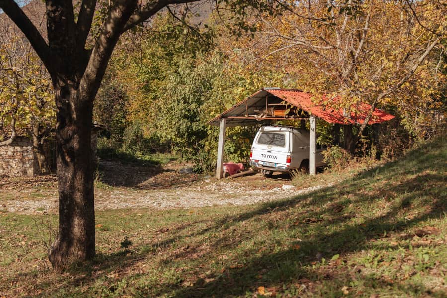 White steel-framed carport canopy with roll-up side panels covering a driveway