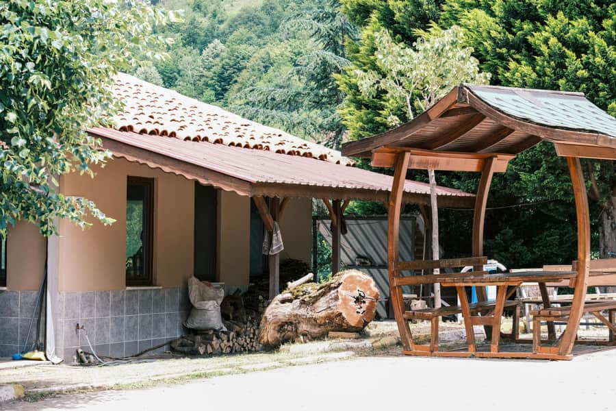 Gray powder-coated hardtop gazebo with a double galvanized steel roof beside a house