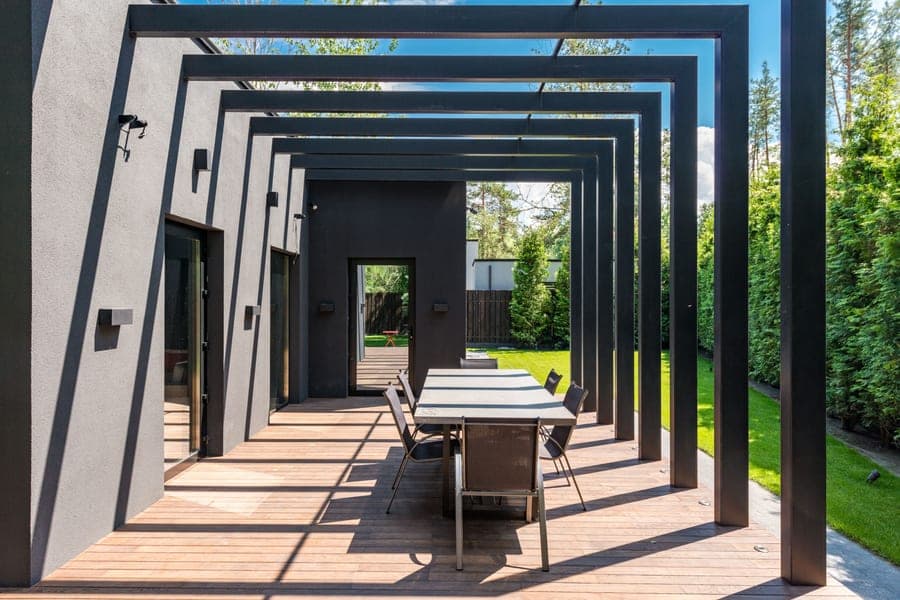 Aluminum louvered pergola with adjustable roof slats over a paved patio, louvers part open
