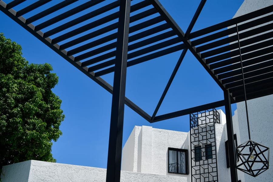 Gray aluminum louvered pergola with closed roof slats anchored to a concrete patio slab