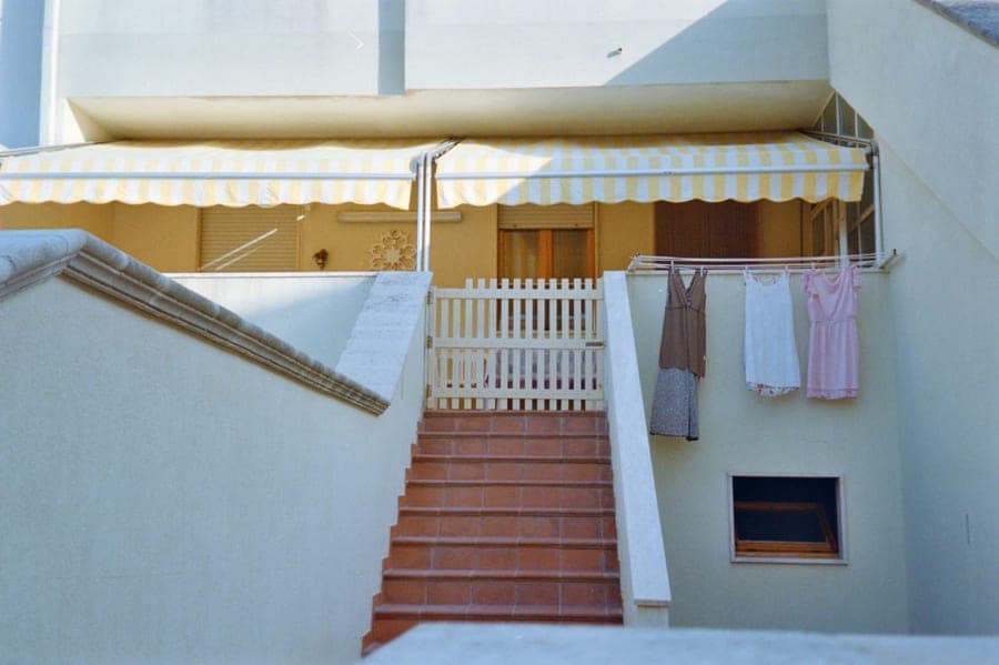 Beige retractable patio awning extended from a house wall over a paved terrace