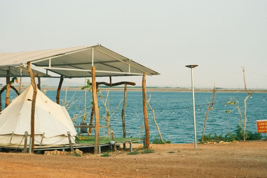 Compact pop-up screen shelter with mesh sides pitched beside a lake