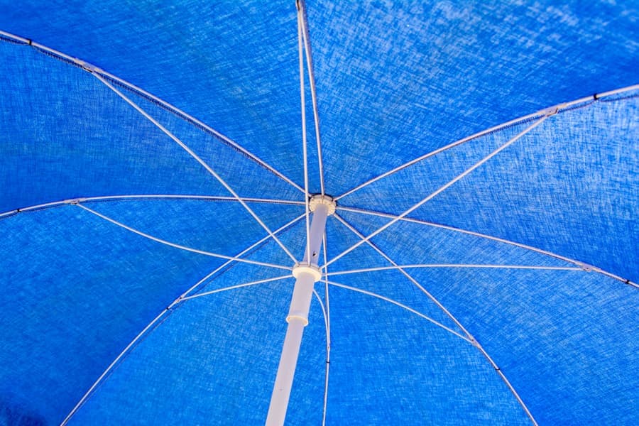 Solid waterproof shade sail angled to shed rainwater over an outdoor dining table
