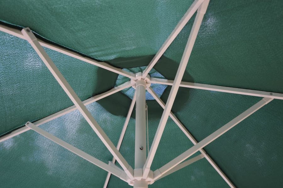 Green woven shade cloth stretched taut showing its open mesh structure against the sky
